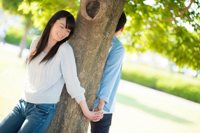 木の下でじゃれ合う大学一年生のカップル
